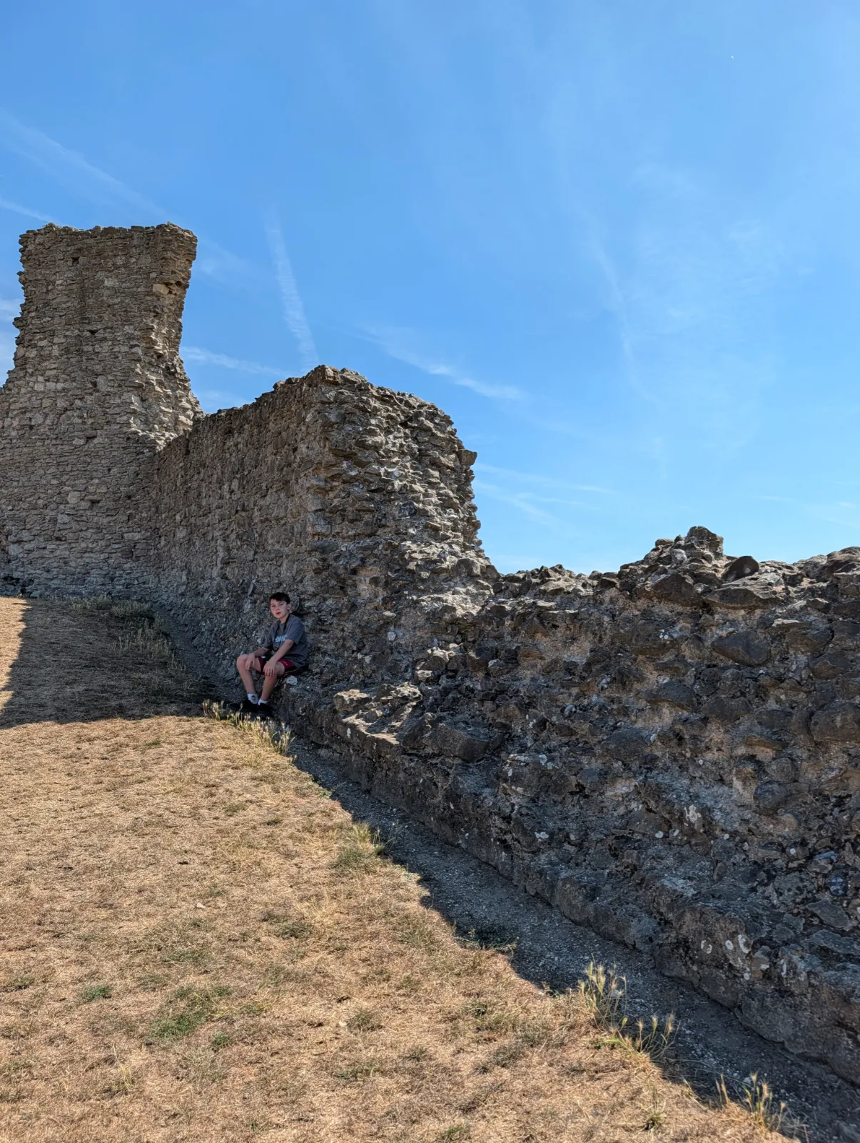 Ruins of Hadleigh Castle beneath a blue summer sky with child sitting near the wall.