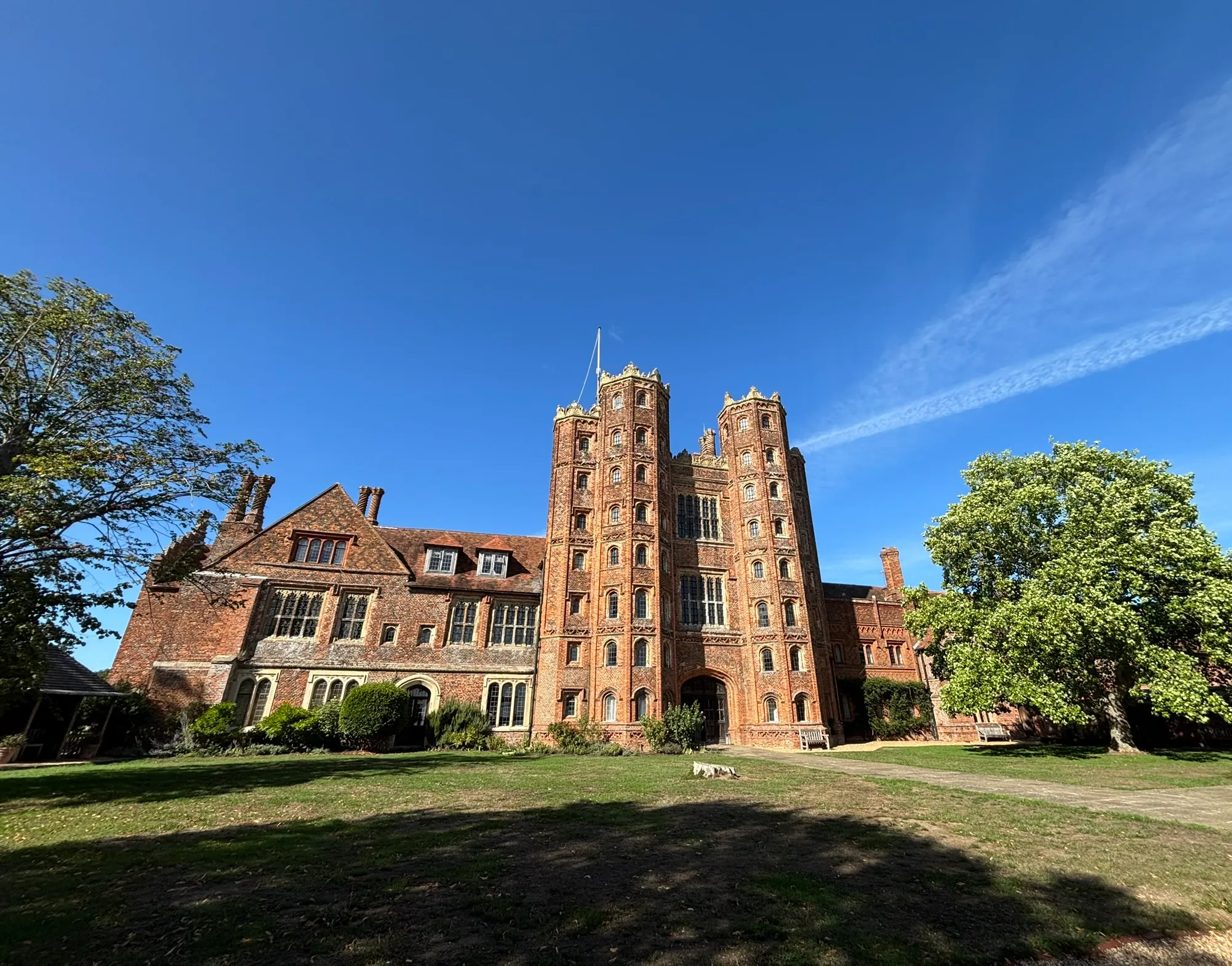 Layer Marney Tower and adjoining historic buildings beneath a clear blue sky.
