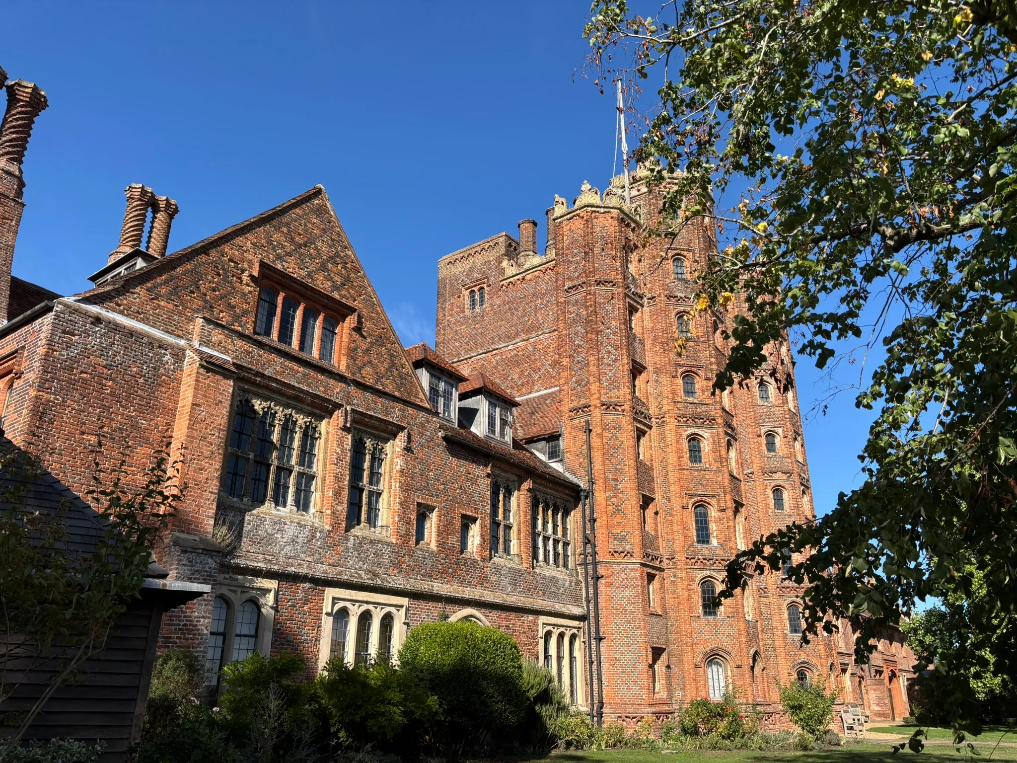 Layer Marney Tower viewed from the grounds beneath a clear blue sky.