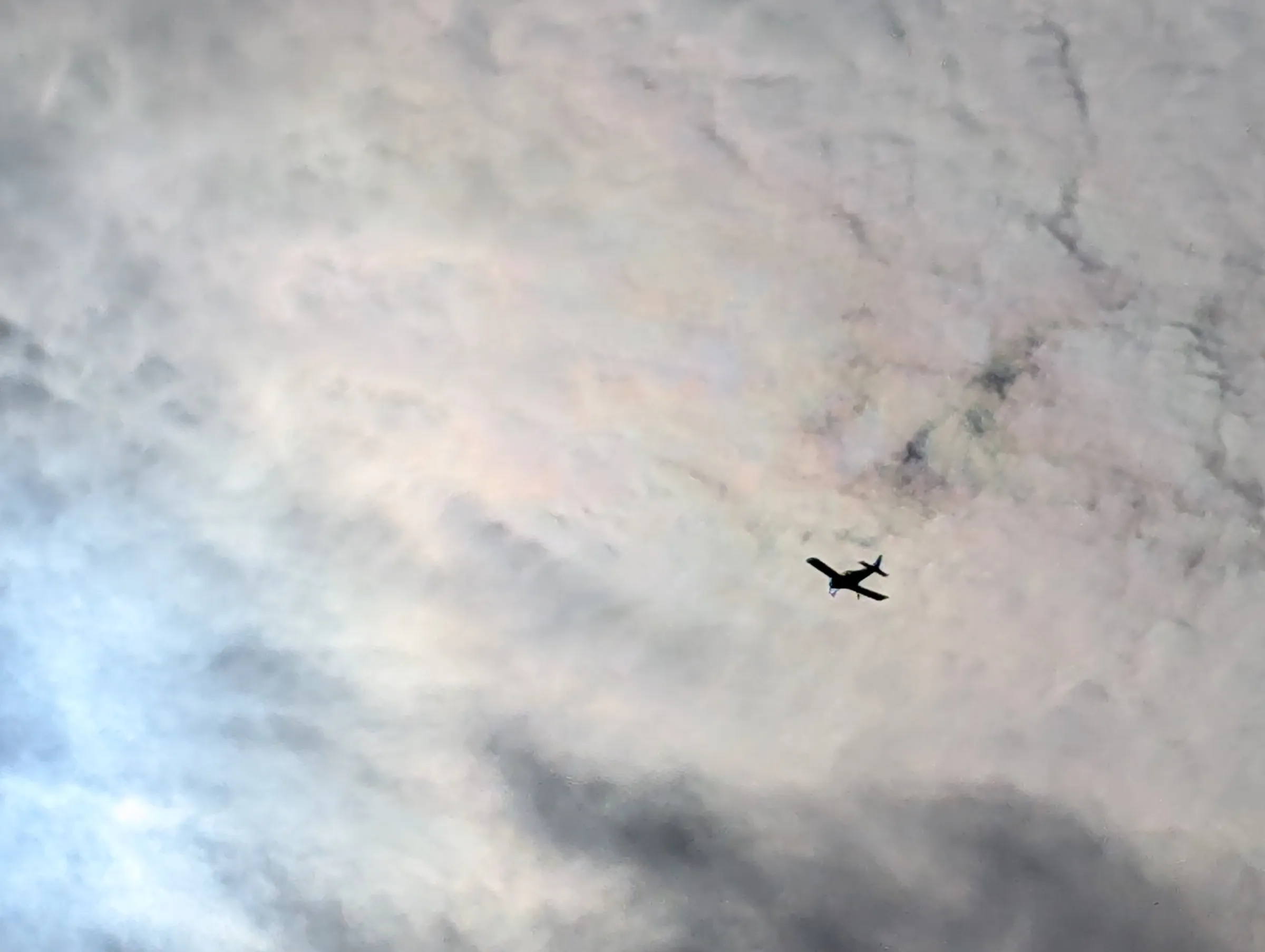 Small aeroplane flying beneath the clouds above Markshall Estate.